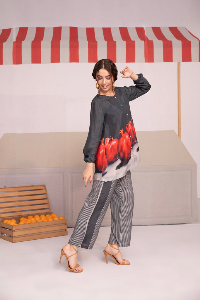 A person wearing a black co-ord set with pomegranate prints, consisting of a long-sleeved top and matching pants